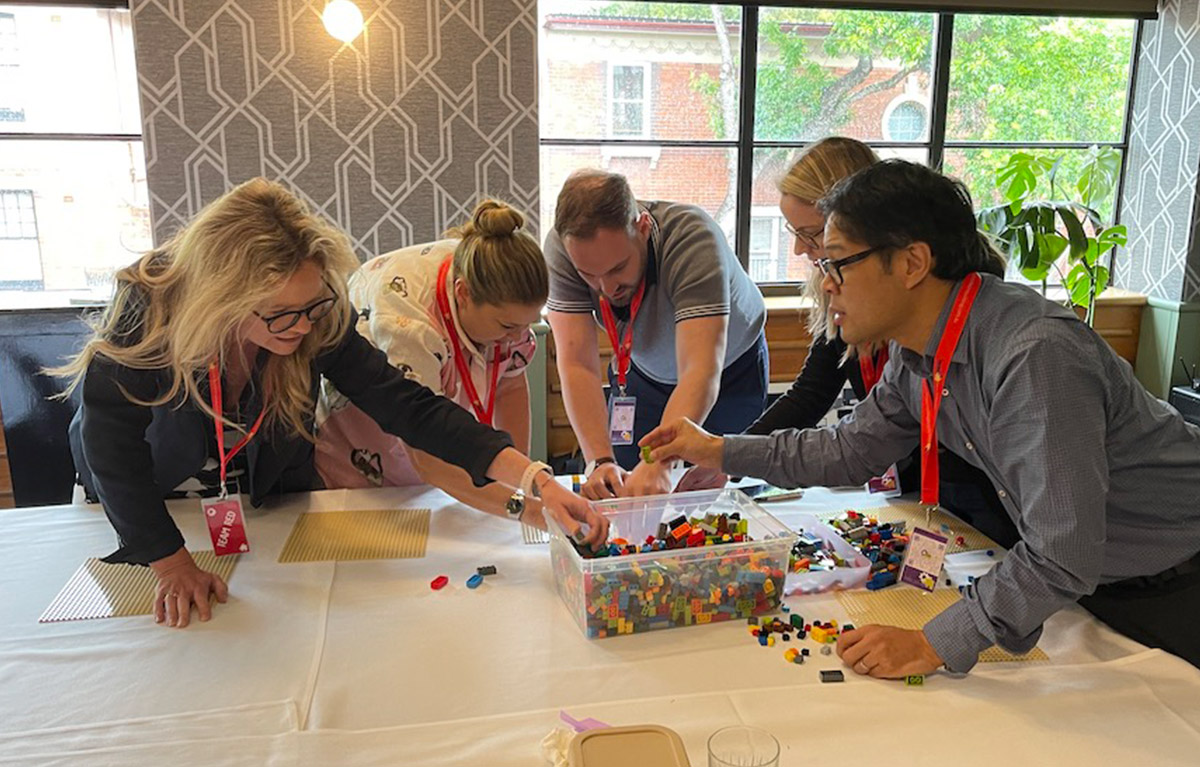 Corporate team building activity with teams competing in LEGO building challenges
