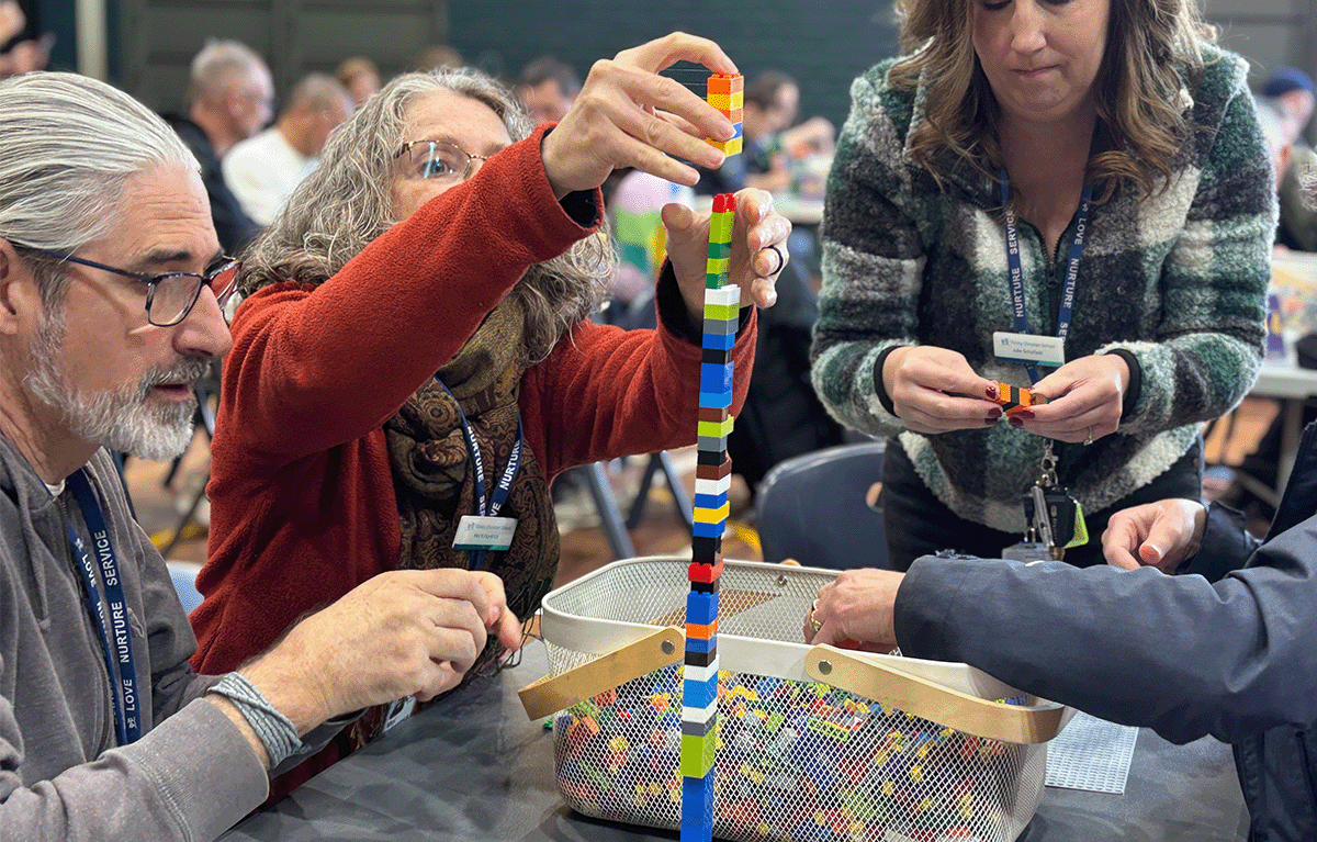 Teams having a laugh whilst building a LEGO tower for a team building activity