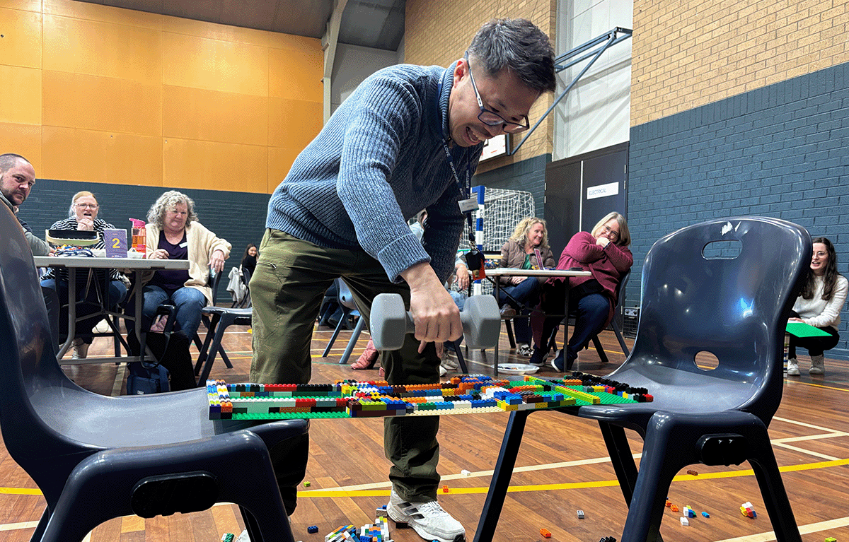 Teams having a laugh whilst building a LEGO bridge for a team building activity